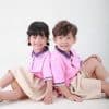 Đồng phục mầm non màu hồng đào phối quần váy sữa - MN104, hai bé ngồi tựa lưng